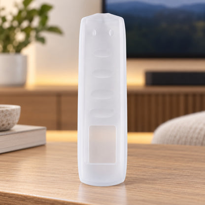 A translucent silicone remote control cover stands vertically on a wooden table in a home entertainment area.