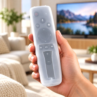 A hand holds a translucent white silicone remote cover over a dark gray remote control in a living room setting.