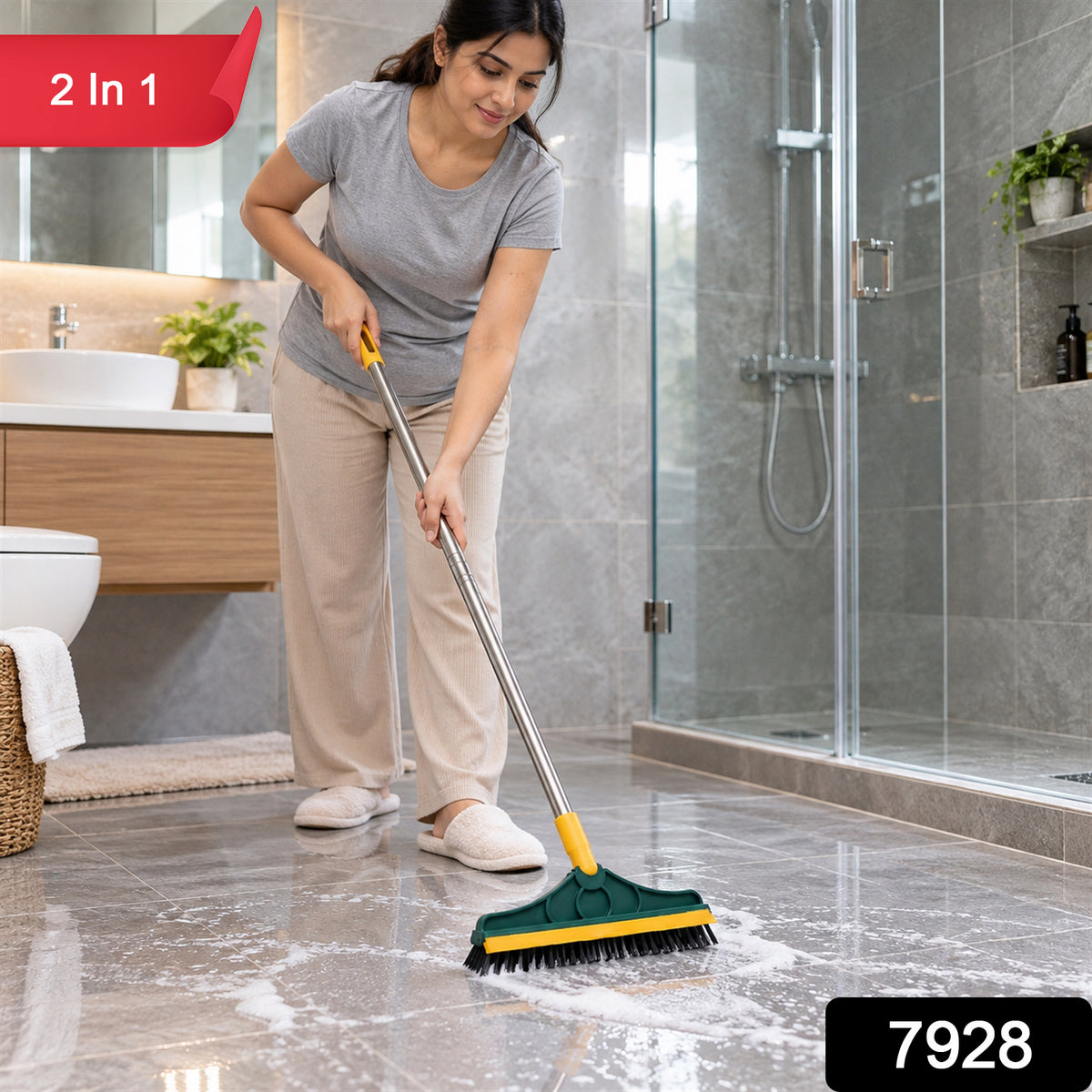 A woman in a grey shirt and beige pants scrubs a tiled bathroom floor with a green and yellow brush, creating white foam. A