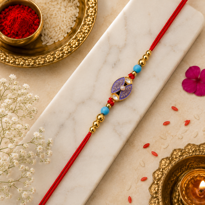 The red thread with its purple and gold oval charm and beads lies on a white marble slab, surrounded by red powder, rice,
