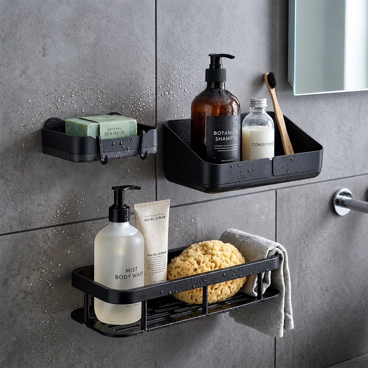 Three black plastic shower caddies holding various bath products and a natural sponge on a dark grey tiled wall.