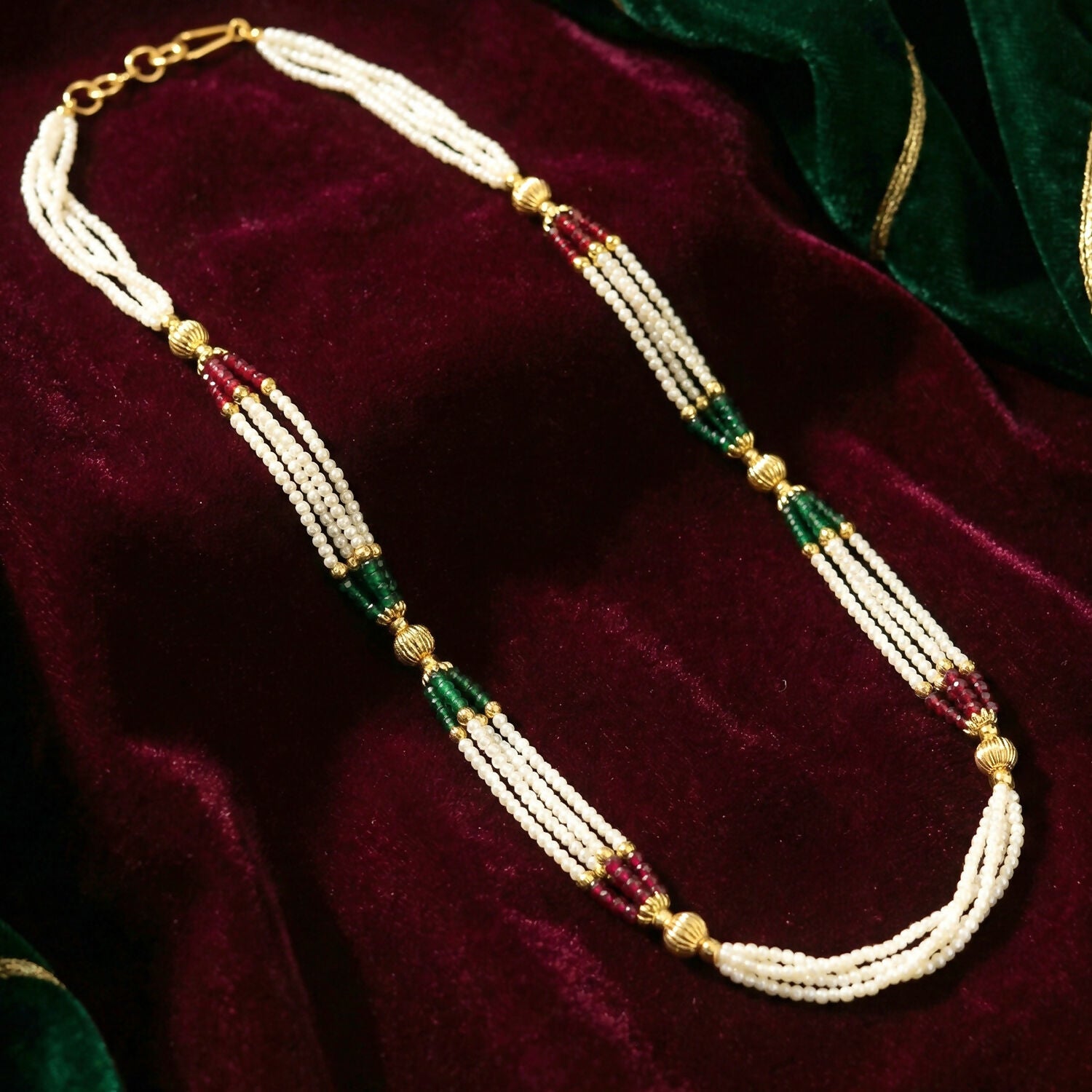 Close-up of pearl strands with red and green bead accents and gold detailing
