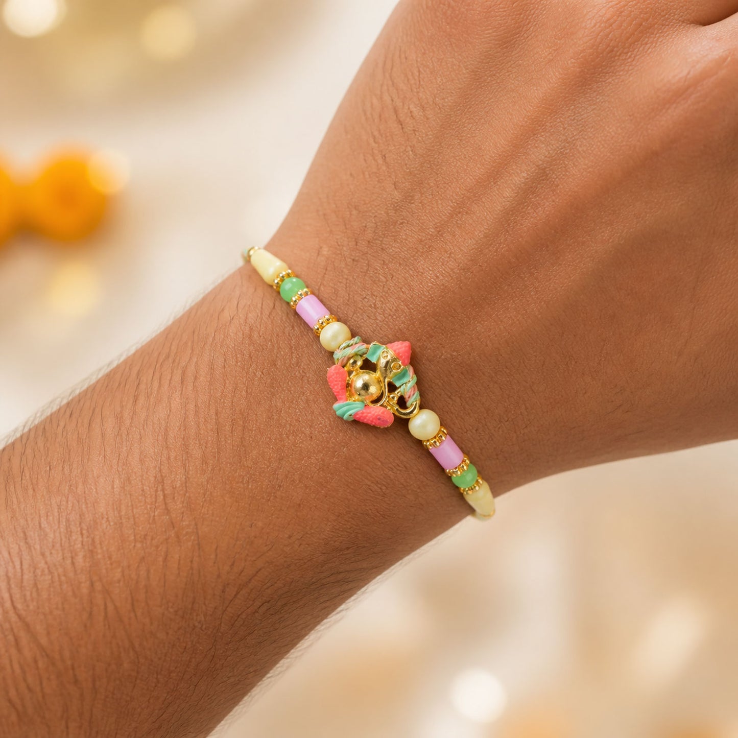 Gold Ganesha Charm Rakhi with Coral and Green Accents