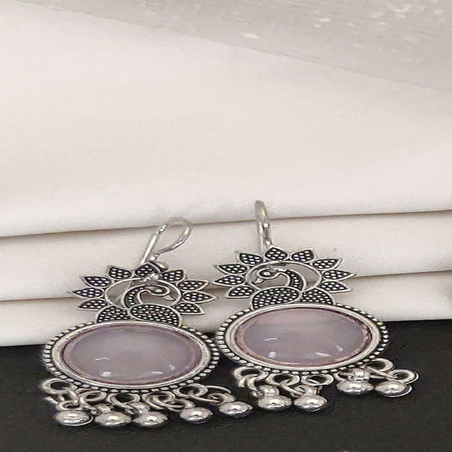 Close-up view of german silver plated oxidized jhumka earrings with peacock motif