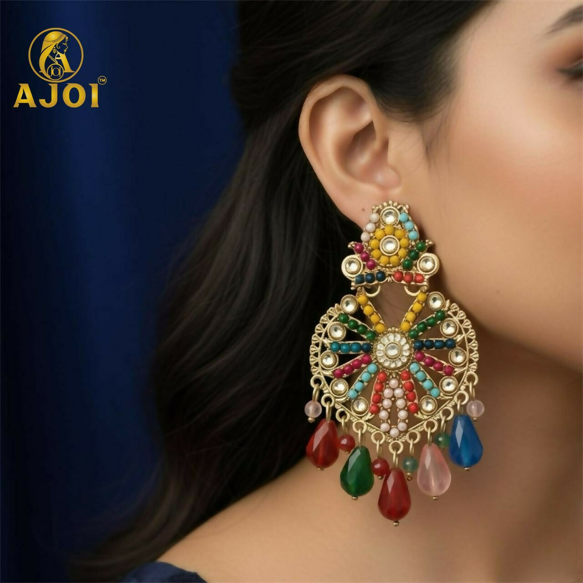 A woman models one large, colorful gold earring with a beaded floral design and dangling teardrops.
