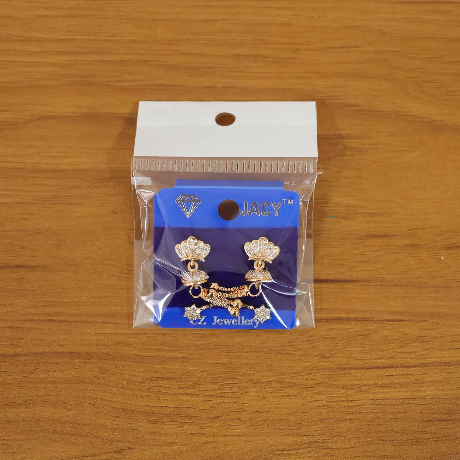 Pair of crown design gold finish earrings with crystal tassels displayed on dark surface