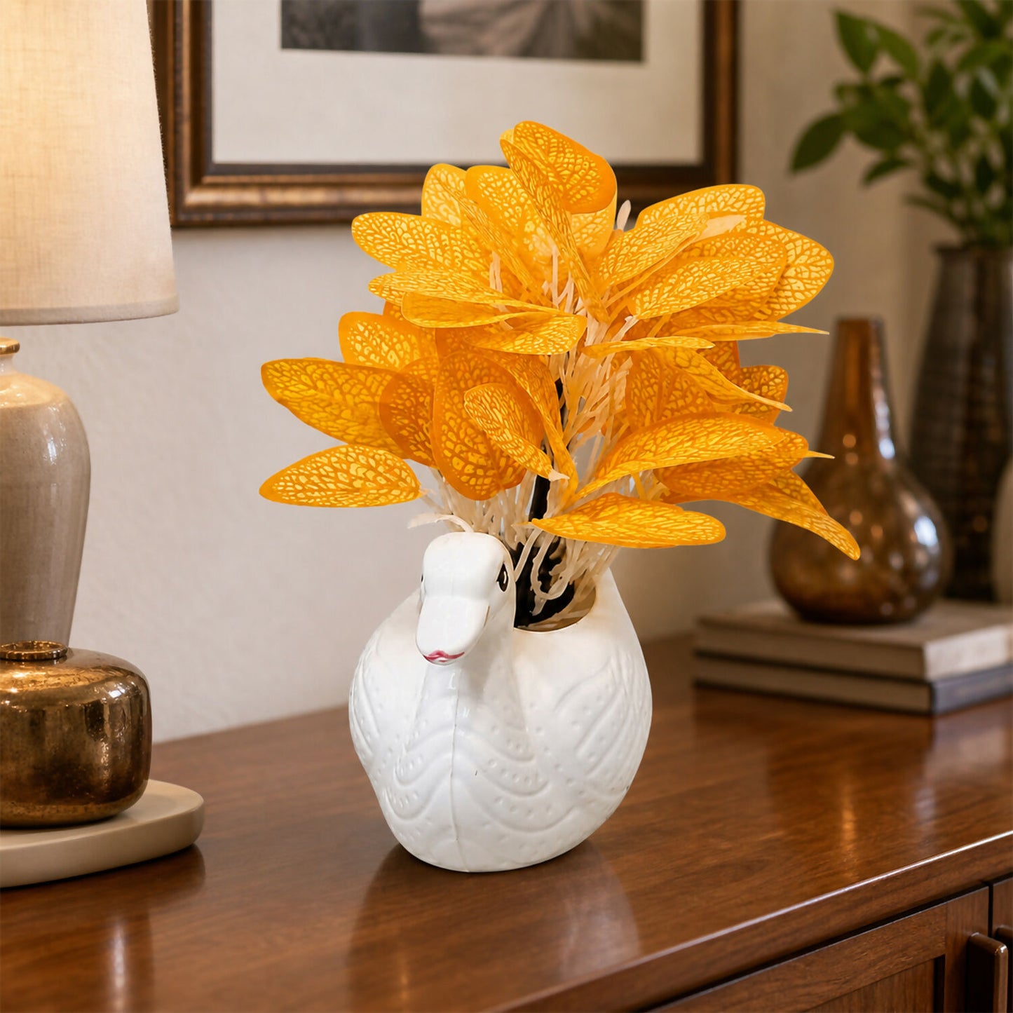 Vibrant orange artificial skeleton leaves arranged inside the white swan vase