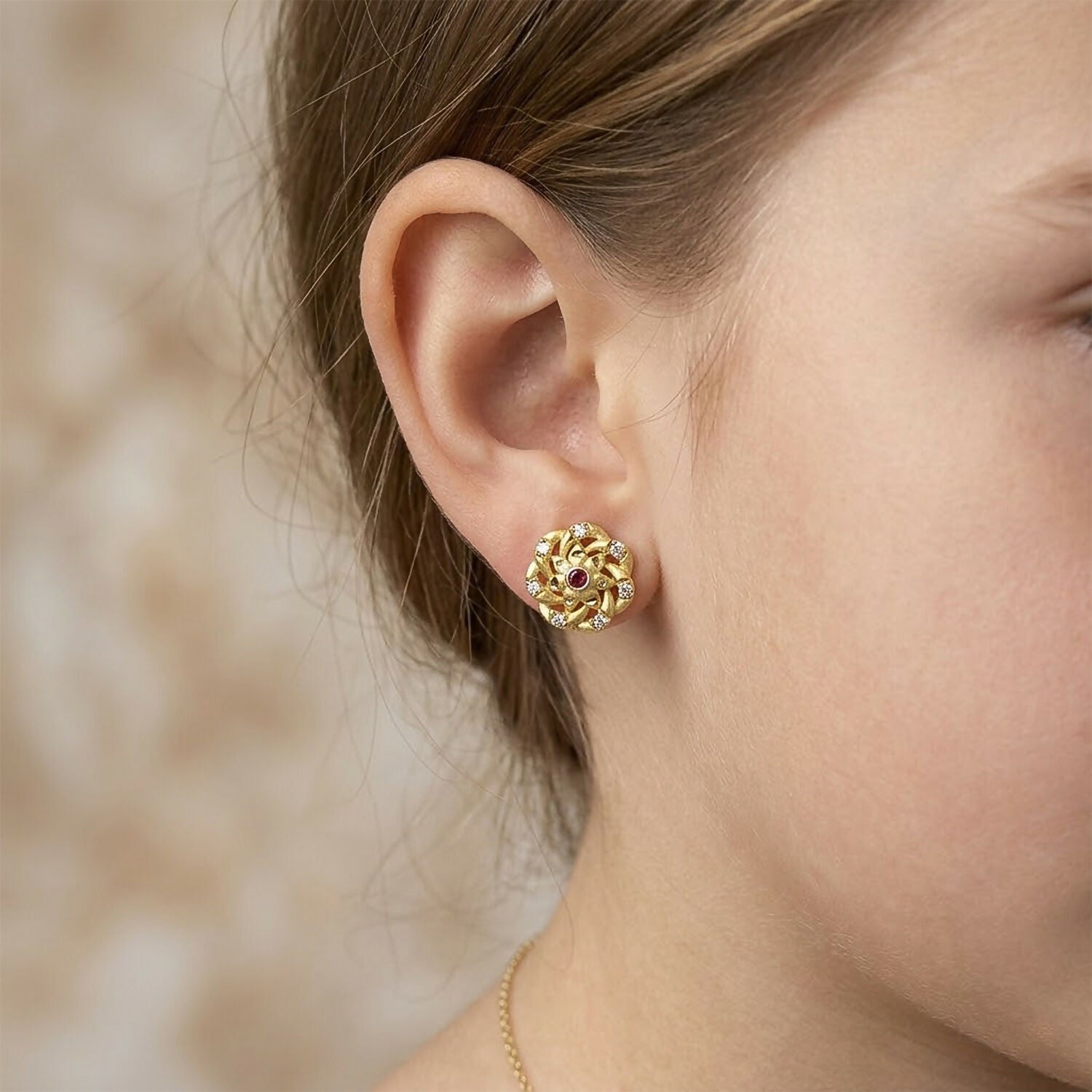 Elegant gold stud earrings featuring intricate floral design with sparkling accents