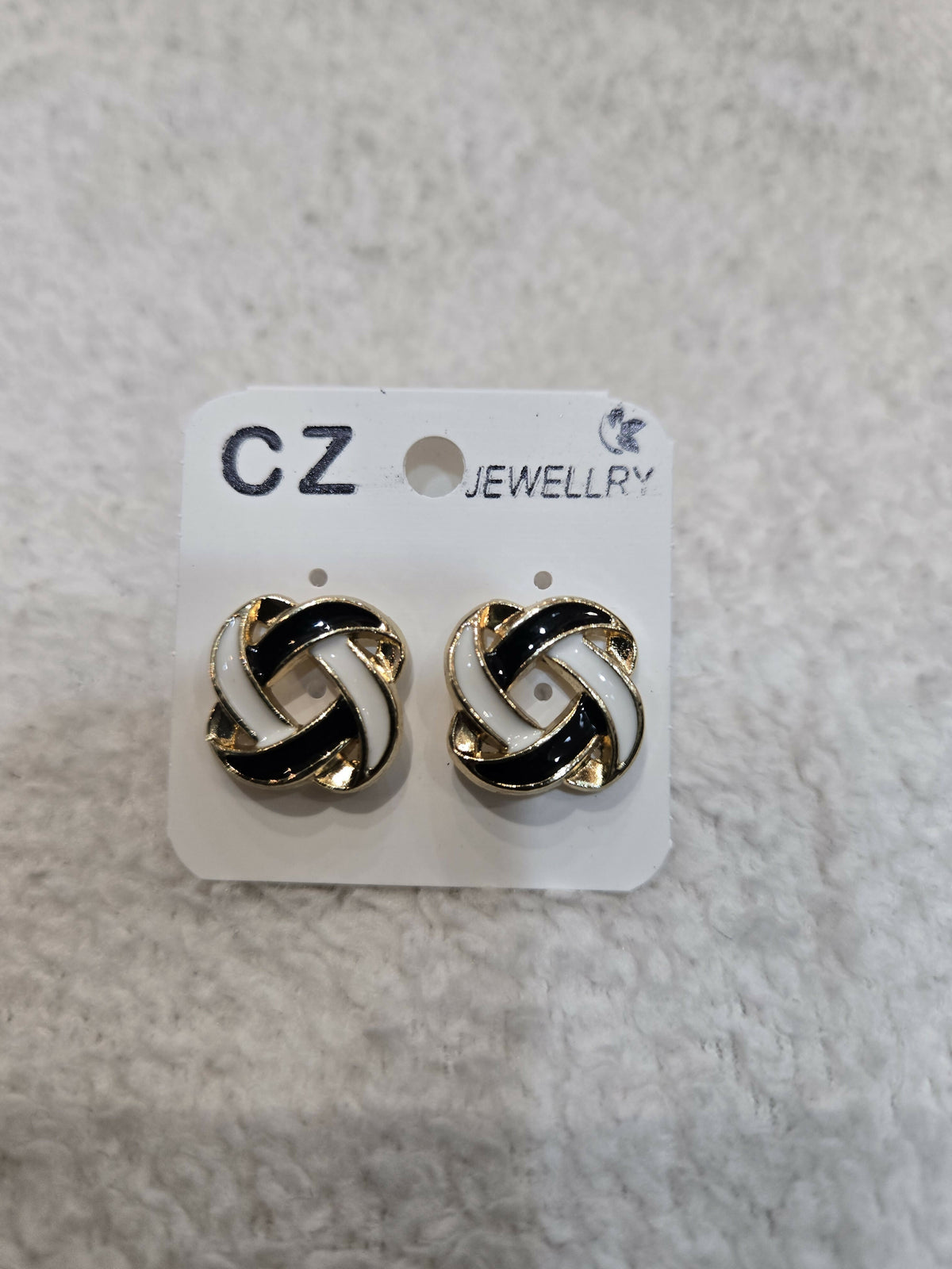 Two black and white enamel knot stud earrings are attached to a white CZ Jewellery card.