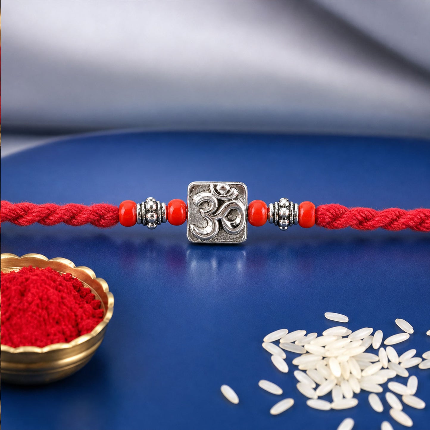 Red Thread Rakhi with a Bold Silver Om Pendant and Red Beads