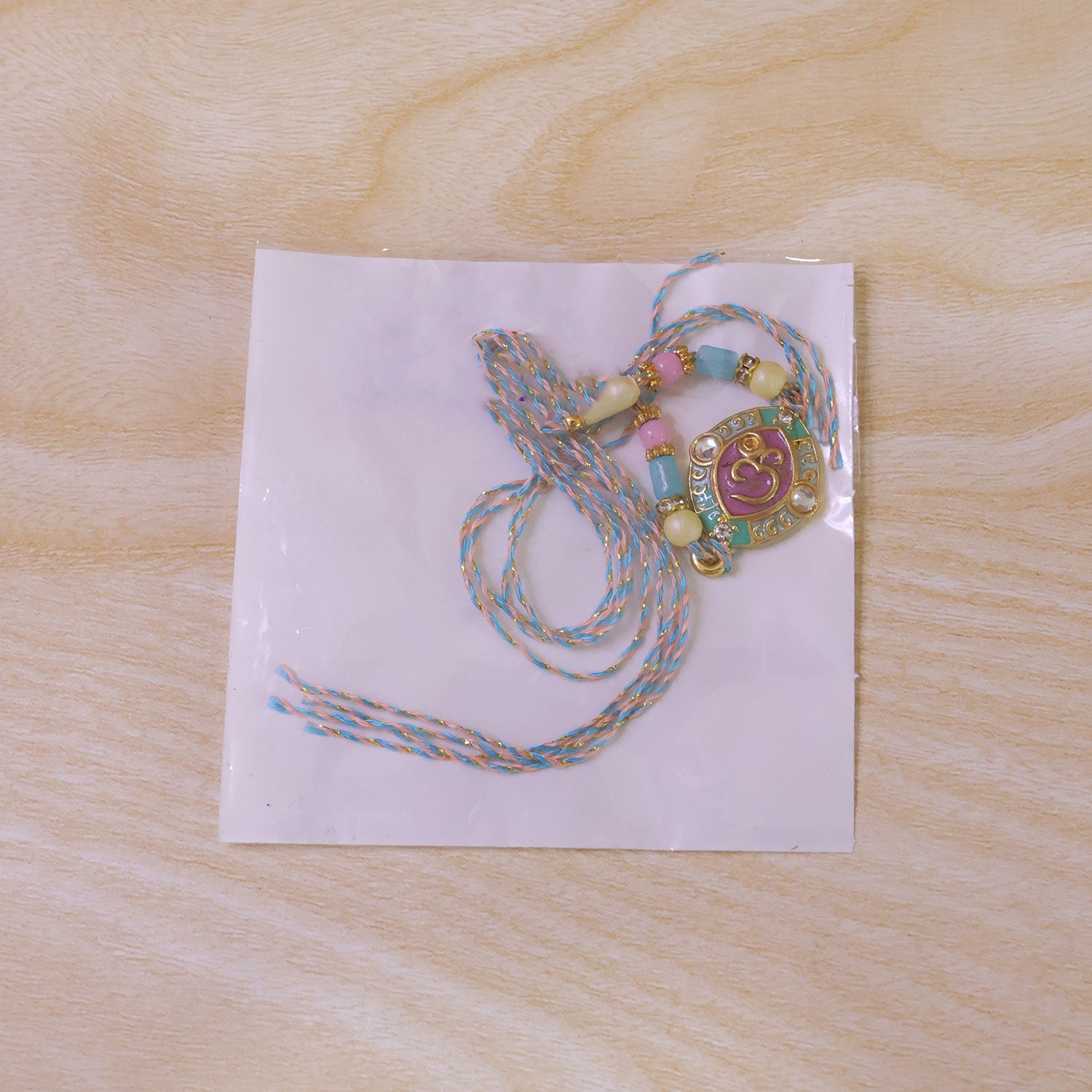Turquoise Om Pendant Rakhi with Pink Kundan and Pastel Beads