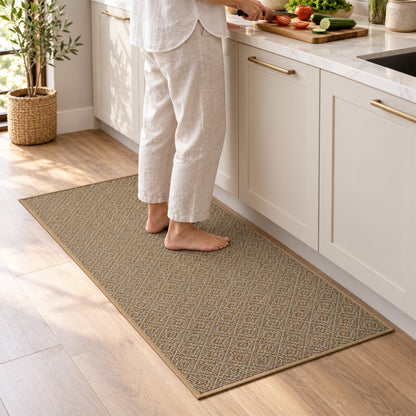 A person stands barefoot on a brown diamond-patterned runner mat in a modern kitchen with white cabinets.
