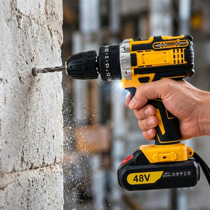 A person's hand holds a yellow and black cordless drill, boring into a concrete wall with dust flying.