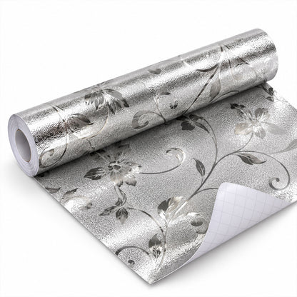 A partially unrolled roll of silver floral textured wallpaper with the grid backing visible on a white surface.