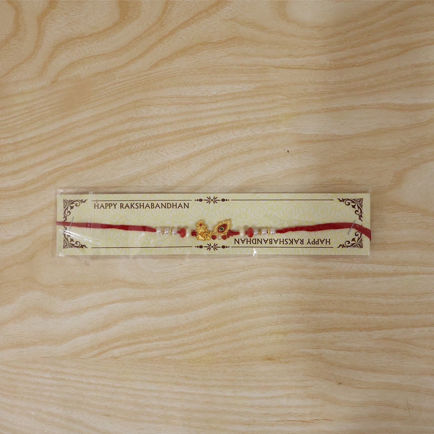 Krishna Mor Pankh Rakhi with Red Pearls and Festive Gold Charm