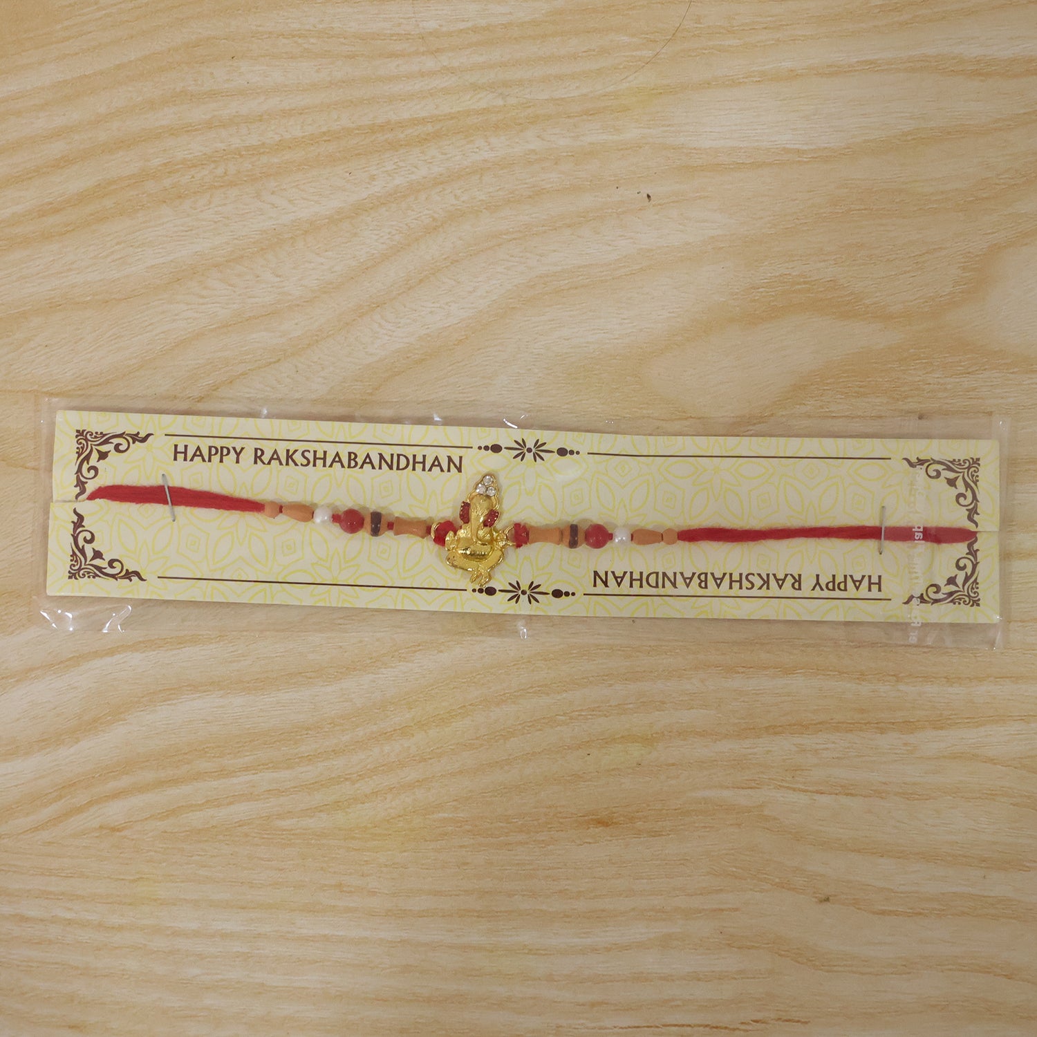 Golden Ganesha Rakhi with Peach Beads and Pearl Accents