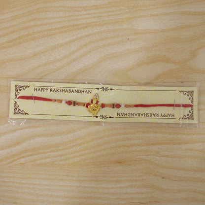 Golden Ganesha Rakhi with Peach Beads and Pearl Accents