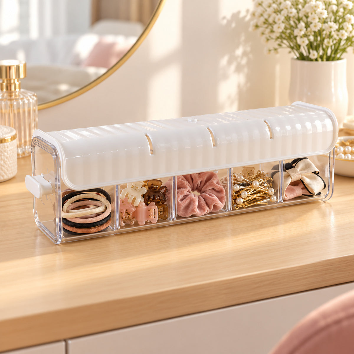 A white and clear plastic organizer with five compartments holds hair accessories on a wooden vanity table.
