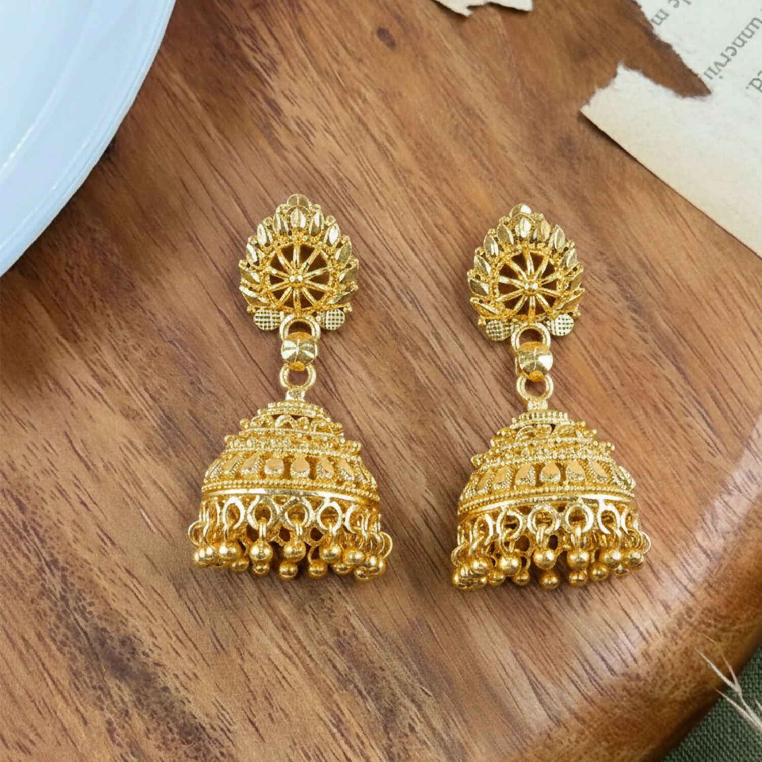 Side view of traditional gold plated jhumka earrings with beads detailed