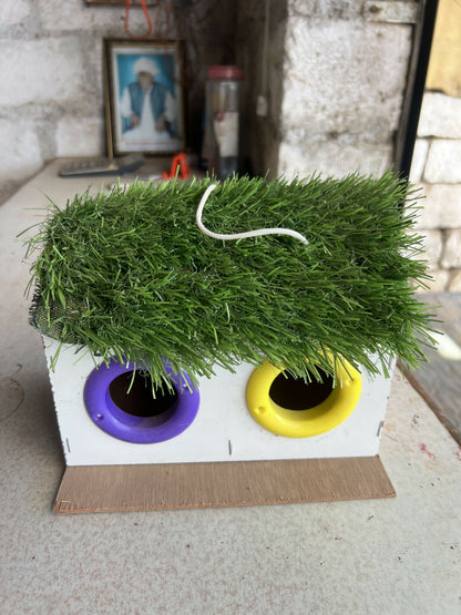 Close-up of handcrafted wooden bird house with artificial grass roof