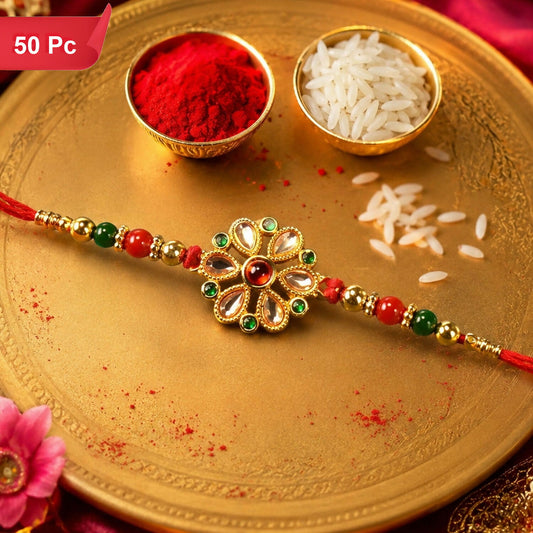 A red thread bracelet with a golden floral centerpiece featuring clear, red, and green stones is displayed on a golden tray