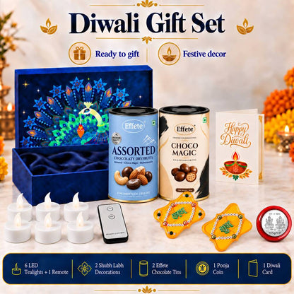 An open blue gift box with a peacock design, two chocolate tins, a Diwali card, six LED tealights, a remote, two yellow