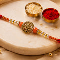 Ganesha Rakhi – Golden Devotional with Orange Beads