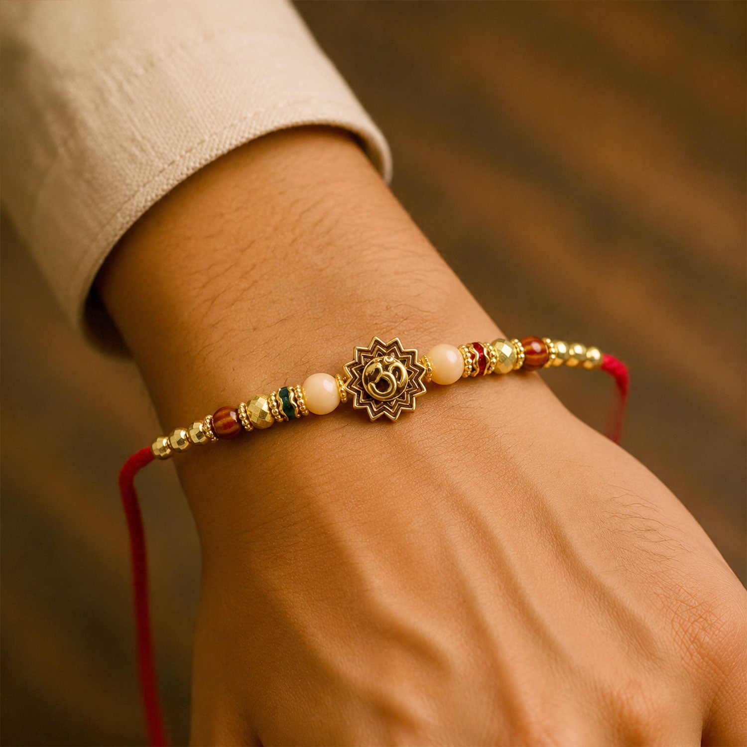 Om Sacred Symbol Golden Devotional Rakhi with Peach Beads and Red Thread