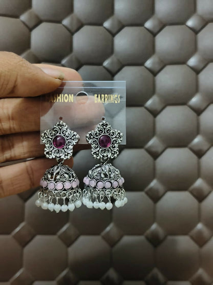 Model wearing oxidized silver jhumka earrings with purple stones and pearl drops