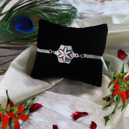 Close up of silver-toned chain Rakhi featuring a delicate flower motif