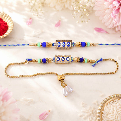 Two blue and gold evil eye rakhis, one a bracelet, on a white surface with pink petals and rice.