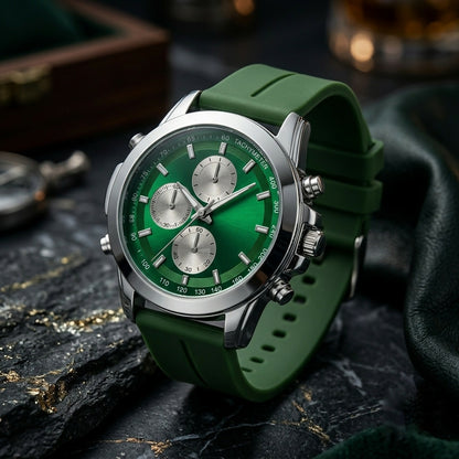 A green and silver watch with a rubber strap, placed on a dark textured surface next to a folded piece of leather.