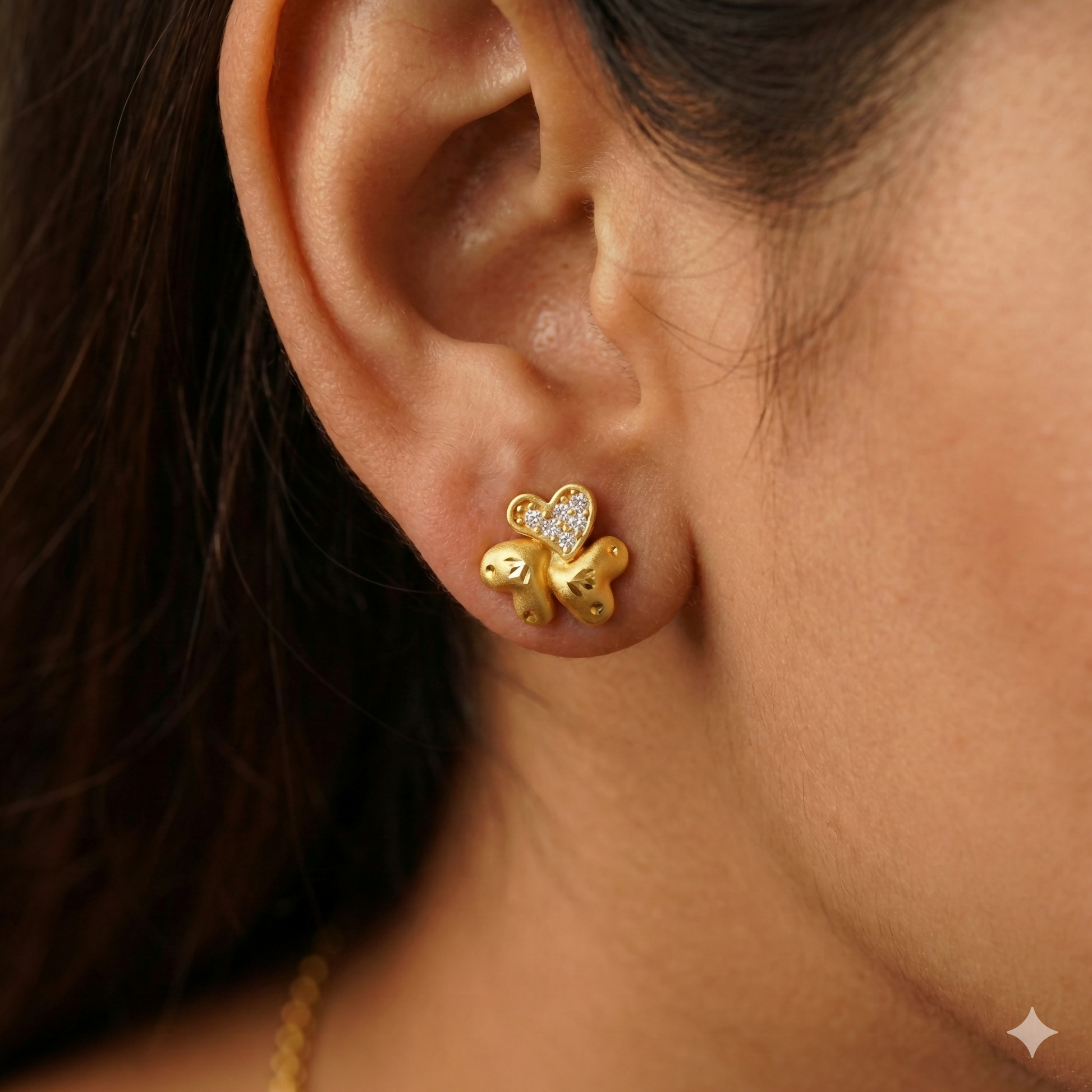 Close-up of gold plated heart motif on floral stud earrings