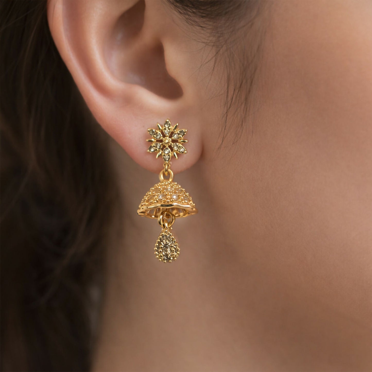 Side view of dome-shaped sunburst floral jhumka earrings with teardrop charm