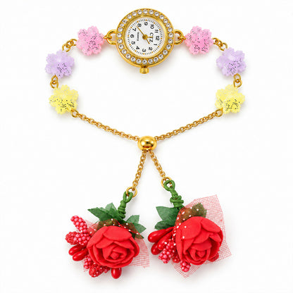 Overhead view of the gold-toned watch with pastel glitter flower links and two red fabric rose charms.