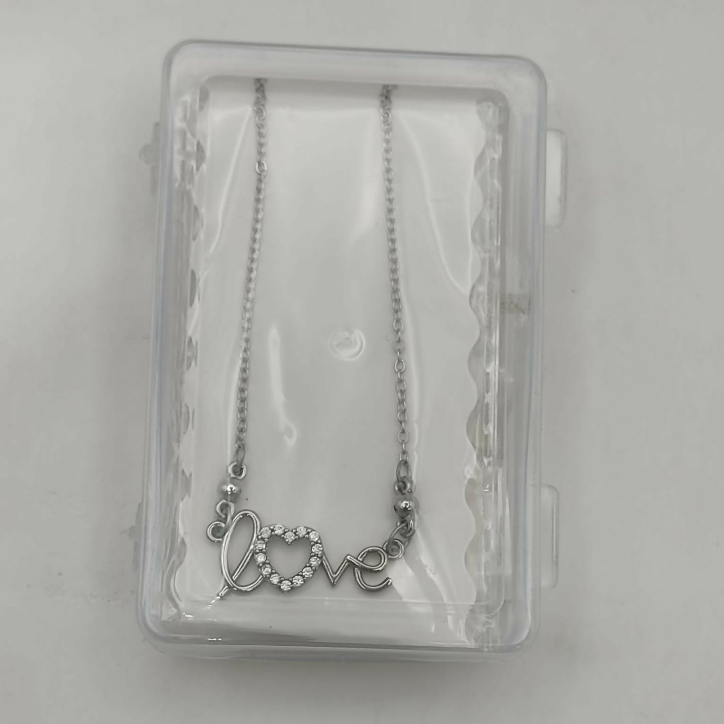 Model wearing silver love script heart pendant necklace with adjustable fine link chain