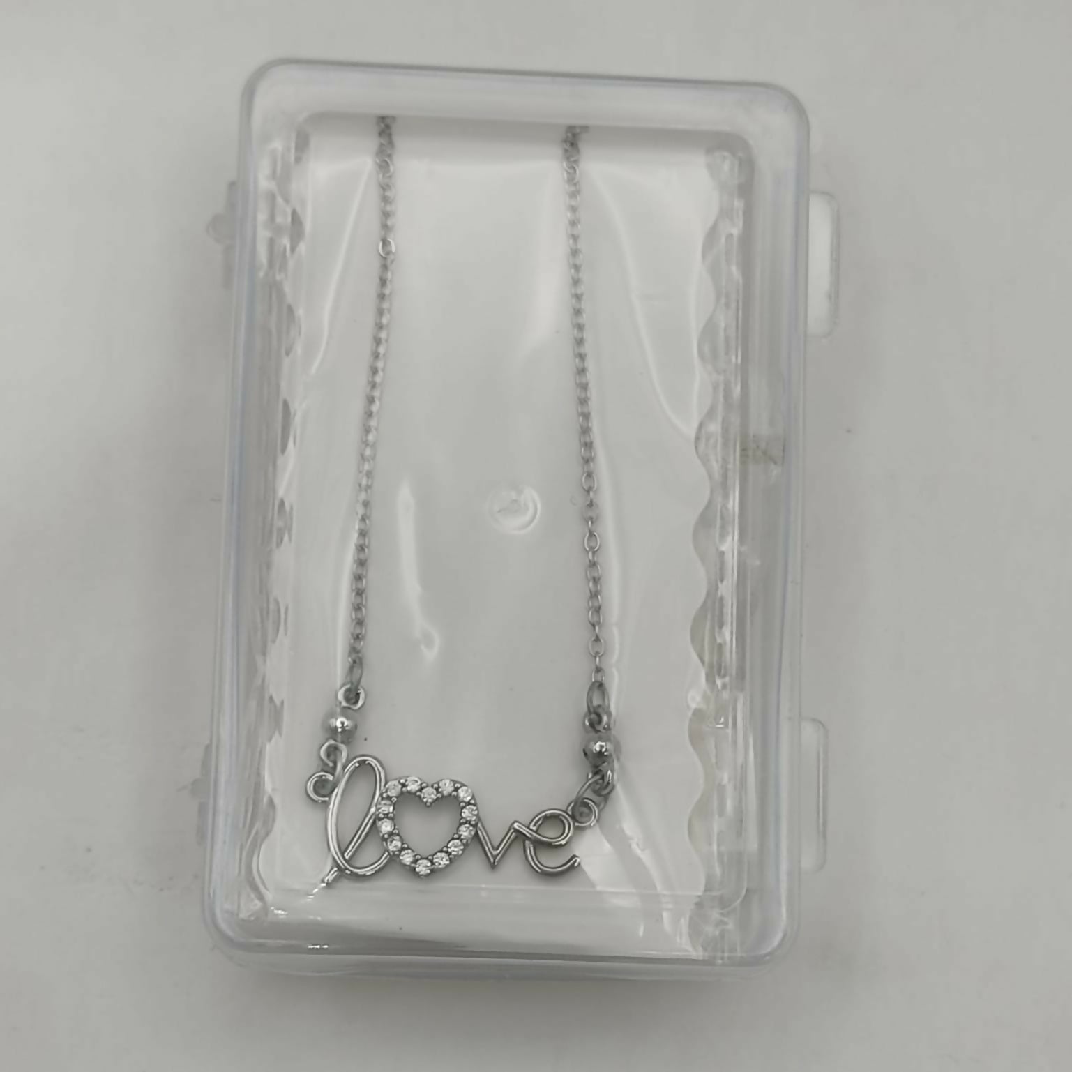Model wearing silver love script heart pendant necklace with adjustable fine link chain