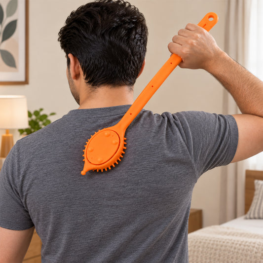 A person uses an orange silicone back scrubber with a long handle on their back in a bedroom setting.