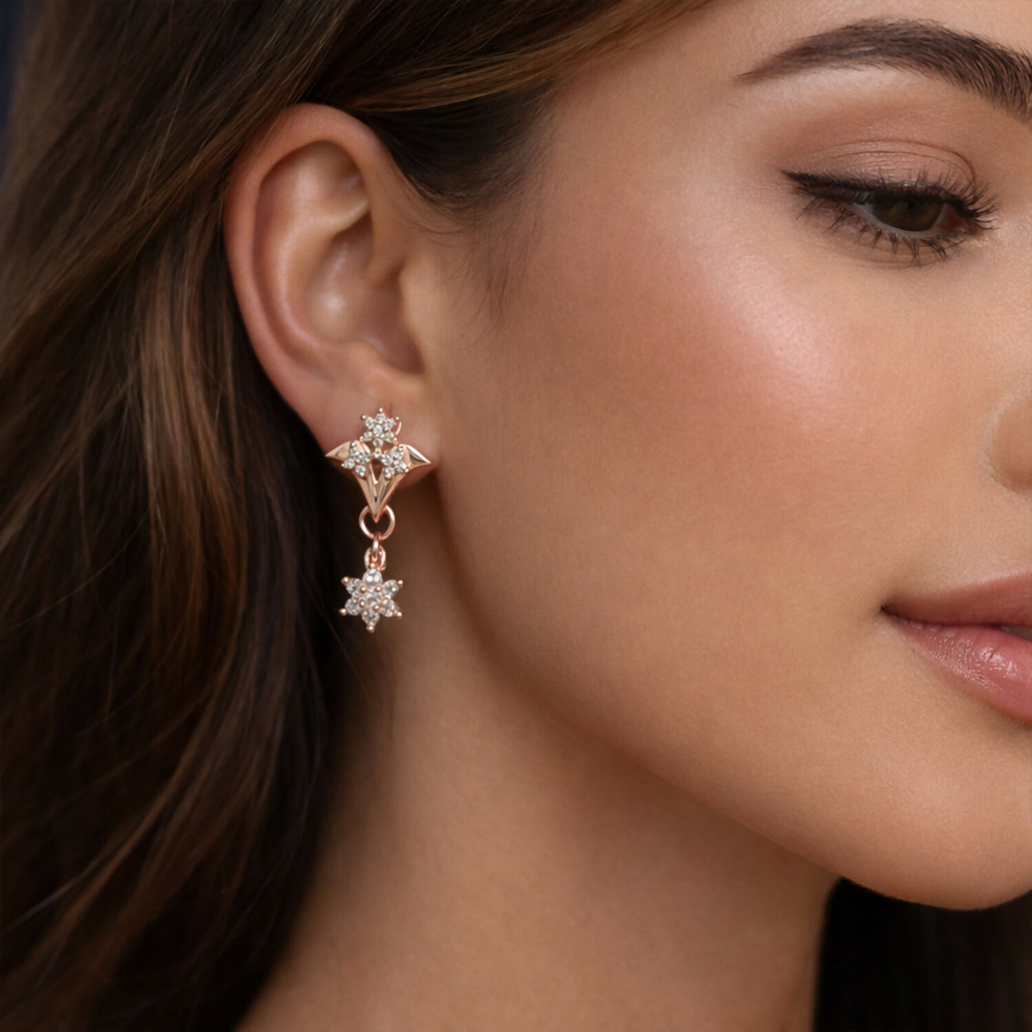 Close-up of rose gold floral star drop earrings sparkling with cubic zirconia