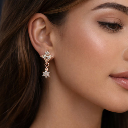 Close-up of rose gold floral star drop earrings sparkling with cubic zirconia