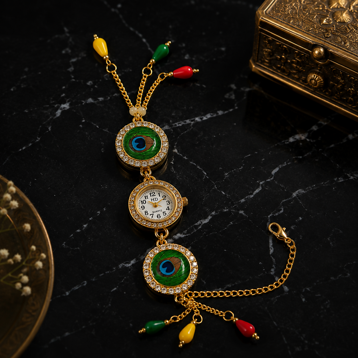 A gold-tone bracelet watch with peacock eye designs, a central watch face, and colorful beads is displayed on a dark marble