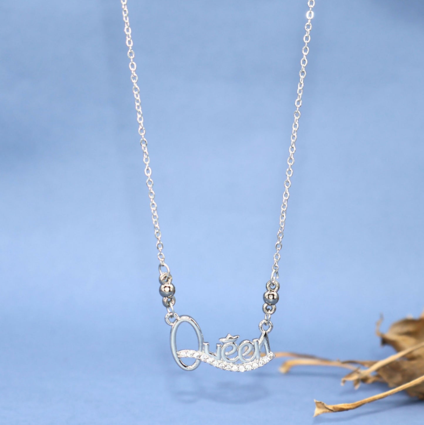 Close-up of Queen script pendant in silver rhodium with glittering Cubic Zirconia stones