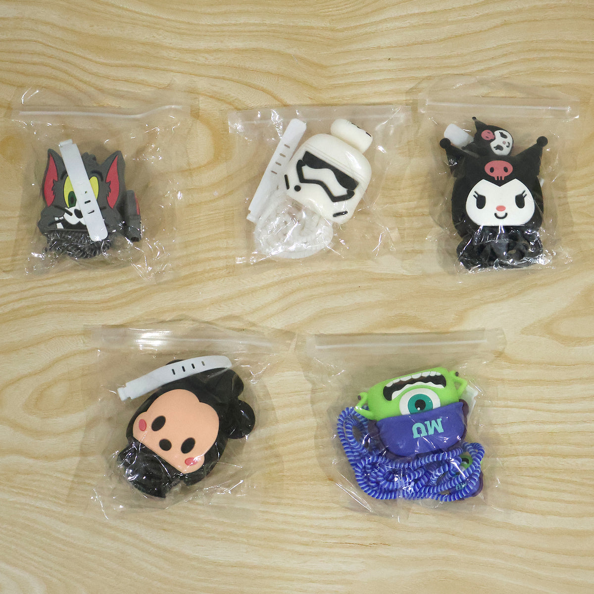 Five different cartoon character silicone charger and cable protector sets individually packaged in clear plastic bags.