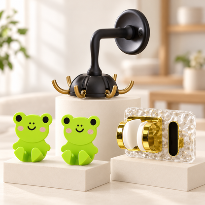A black six-hook wall mount, two green frog-shaped cable holders, and a clear and gold mop gripper on white pedestals.