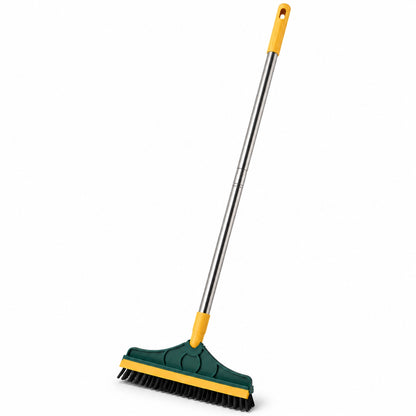 A green and yellow floor cleaning brush with a long metal handle is angled on a white background, showcasing its design.