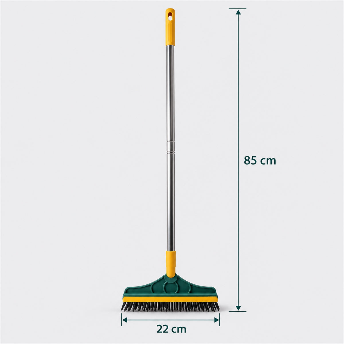 A green and yellow floor cleaning brush with a metal handle stands upright on a grey background, with measurements