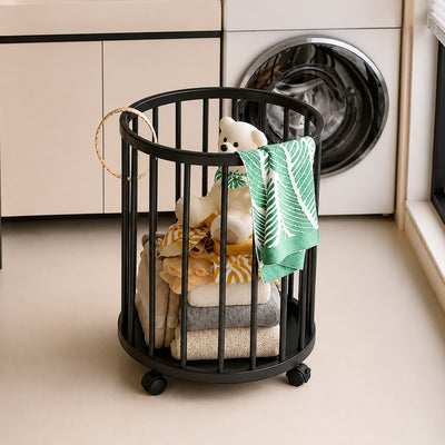 Black metal laundry basket with vertical bars, full of folded clothes and a teddy bear, in a modern laundry room.
