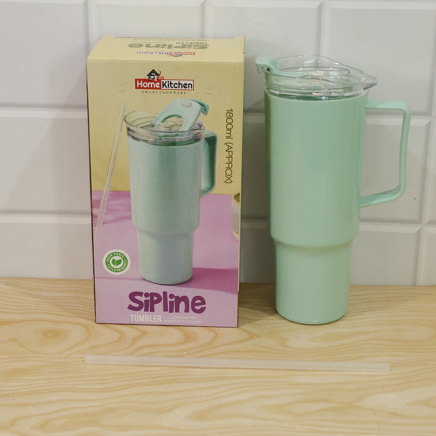 A mint green tumbler with a straw and handle next to its product box, on a wooden surface.