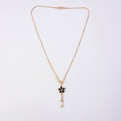 Gold finish necklace featuring black floral pendant with stones and hanging drop