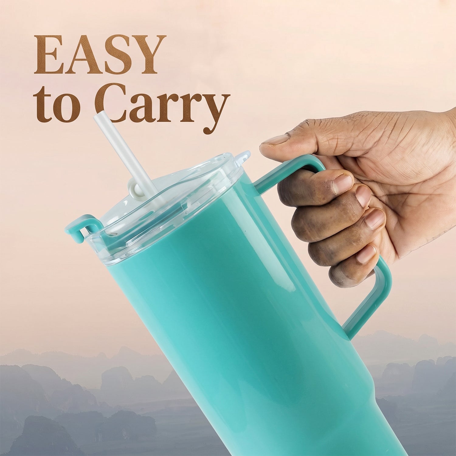 A hand holds the handle of an aqua blue tumbler with a clear lid and straw against a blurred, warm-toned background with the